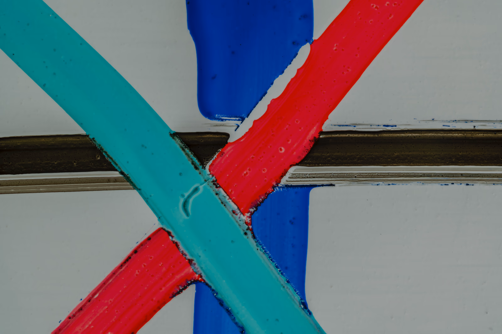 Four dry-erase marker strokes crossing, a few millimeters wide, under the macro rig.